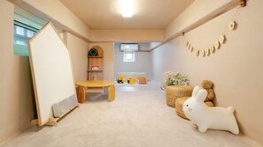 A child's playroom with a wooden table, toys, a clock, and a wall decoration. - Gangneung Staymeet Private Pool Villa (Gangneung)