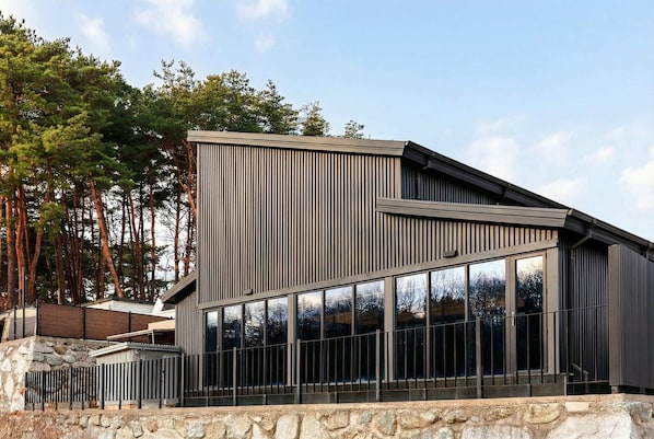 Een modern gebouw met een schuin dak, grote ramen en een stenen basis.