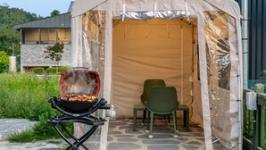 Een tent met een grill, een stoel en een stenen vloer.