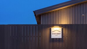 Een gebouw met een gevlinderde metalen buitenkant en een verlicht bord waarop 'STAY MEET' staat.