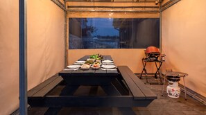 Een eethoek met een gedekte tafel, een barbecue en een draagbaar gasfornuis.