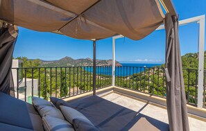 A balcony with a view of the sea and mountains, a bed with pillows, and a canopy. - Beach front home in Canyamel (Canyamel)