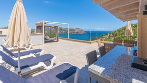 Una terraza en la azotea con sillones, una mesa y vistas al mar.