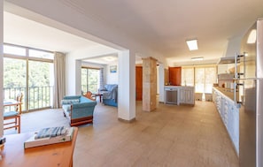 A spacious living area with a balcony, a dining table, and a kitchen area with modern appliances. - Beach front home in Canyamel (Canyamel)