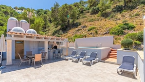 Un patio exterior con piscina, sillas de descanso y zona de barbacoa.
