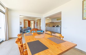 A spacious dining area with a wooden table and chairs, a kitchen in the background, and a view of the living area. - Beach front home in Canyamel (Canyamel)