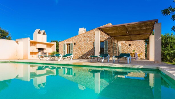 Eine moderne Villa mit Pool, Sitzgelegenheiten im Freien und Steinwänden.