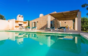 Een moderne villa met zwembad, terras en stenen muren.
