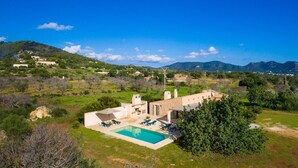 Eine Villa mit Swimmingpool, Sitzgelegenheiten im Freien und Blick auf die umliegende Landschaft.