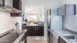 Una cucina moderna con mobili scuri, piano cottura integrato e frigorifero in acciaio inossidabile.