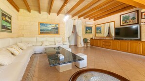 Una sala de estar con un sofá, una mesa de centro, un televisor y obras de arte en las paredes.