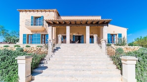 Une maison à deux étages avec un escalier en pierre menant à l’entrée.