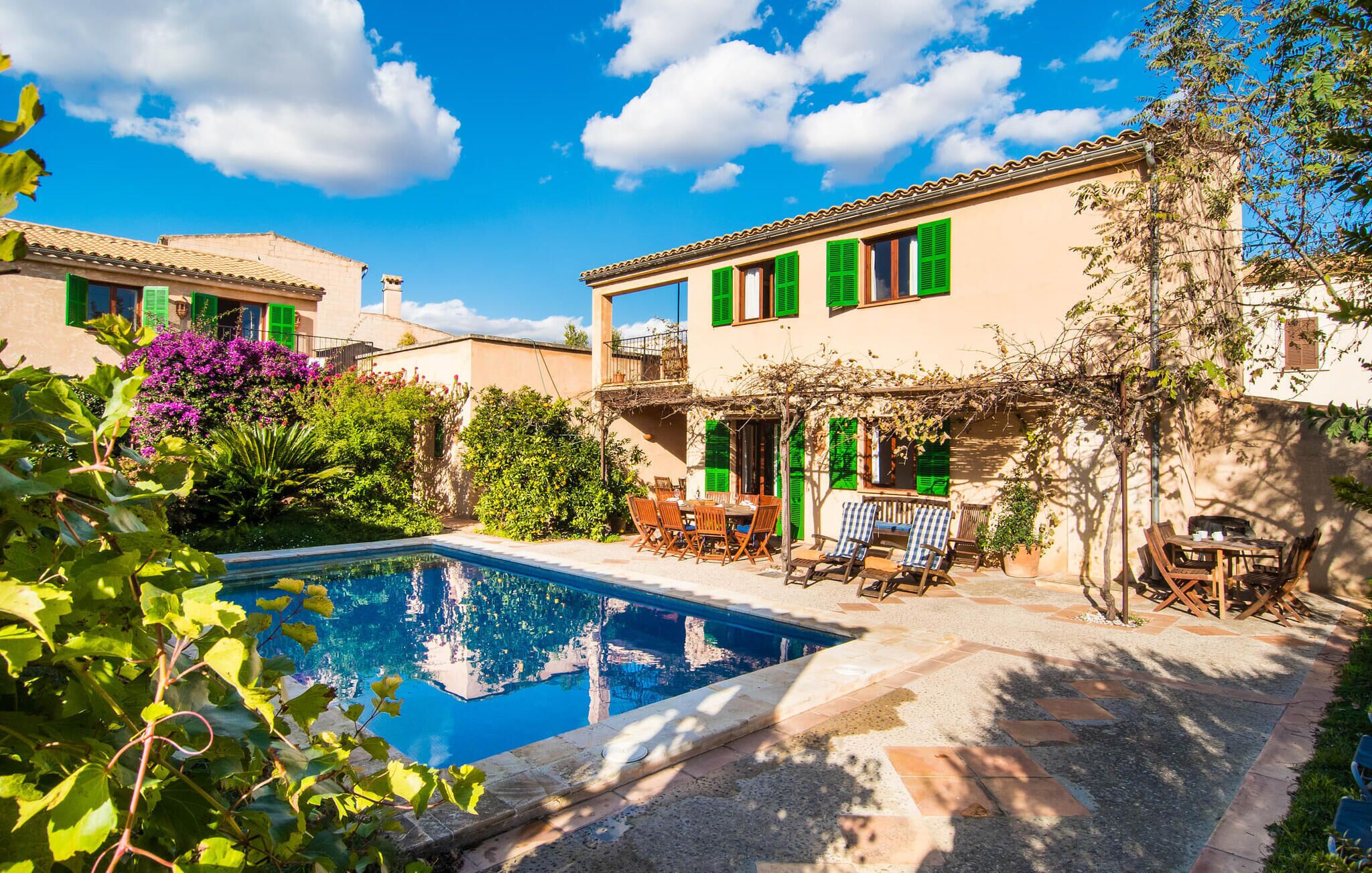 A villa with a swimming pool, outdoor seating, and lush greenery.