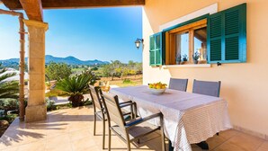 Eine Terrasse mit Tisch für zwei Personen, Blick auf die Landschaft und ein Gebäude mit grünen Fensterläden.