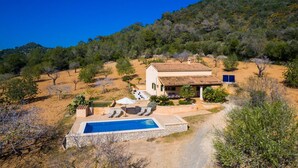 Eine Villa mit Swimmingpool, Sitzgelegenheiten im Freien und Blick auf eine hügelige Landschaft.