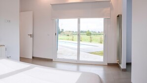 Un dormitorio moderno con un amplio ventanal corredera que da a un patio.