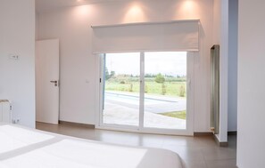 Une chambre moderne dotée d’une grande porte-fenêtre coulissante donnant sur un patio.