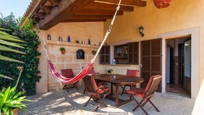 Eine Terrasse im Freien mit einem Holztisch, Stühlen, einer Hängematte und einer Steinmauer.