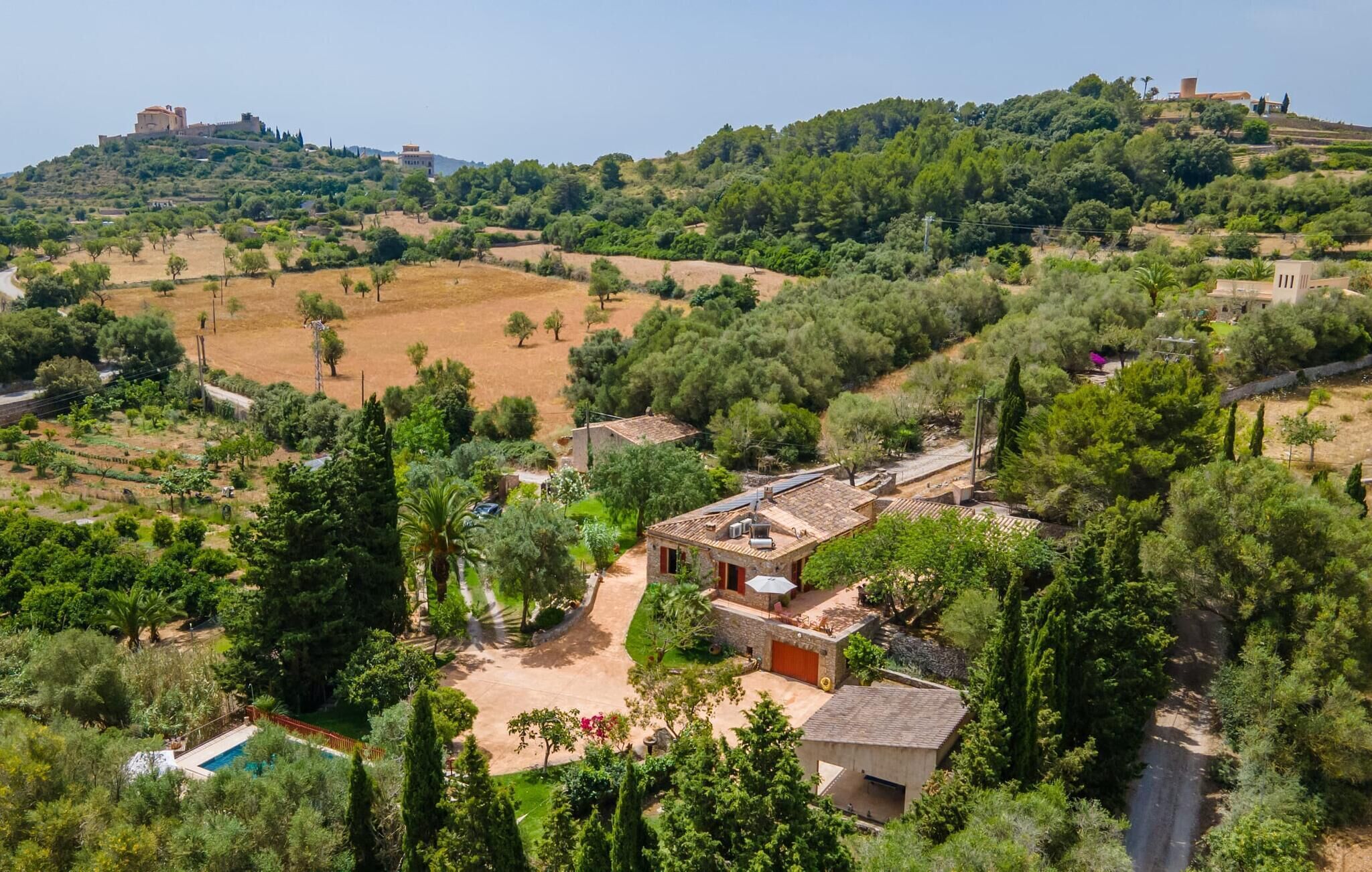 A villa with a swimming pool, surrounded by lush greenery and hills.