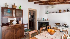 A traditional dining room with a wooden table, chairs, and a fireplace. There is a cabinet with glass doors and a shelf with various decorative items. - Gorgeous home in Sant Llorenc (Sant Llorenc)