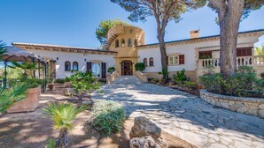 A Mediterranean-style building with a stone courtyard, arched windows, and a central tower. - Amazing home in Sa Font de Sa Cala (Sa Font de Sa Cala)