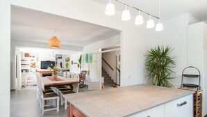 Une cuisine moderne dotée d’un îlot central, de meubles blancs et d’un escalier menant à un autre niveau.
