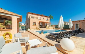 A pool area with lounge chairs, a table, and umbrellas. - Amazing home in Portocolom with private swimming pool, can be inside or outside (Portocolom)
