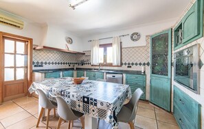 A kitchen with a tiled backsplash, a dining table with a patterned tablecloth, and teal cabinets. - Amazing home in Portocolom with private swimming pool, can be inside or outside (Portocolom)