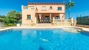 Ein zweistöckiges Haus mit einem Schwimmbecken davor.
