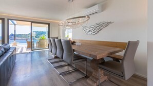 Un espace de salle à manger moderne avec une table en bois, des chaises à revêtement gris et un lustre.