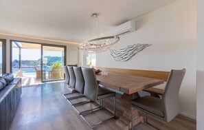 Ein moderner Essbereich mit einem Holztisch, grau gepolsterten Stühlen und einer Kronleuchter.