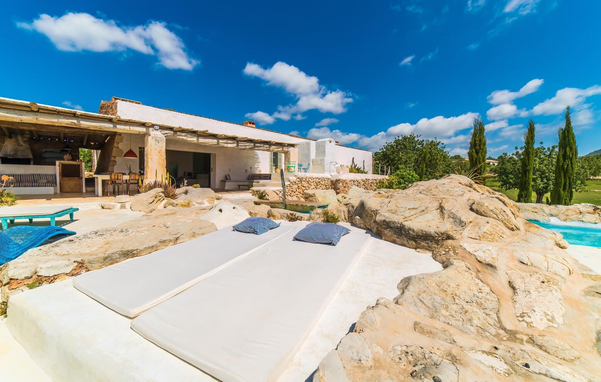 Uma vila com piscina, área de estar externa e muro de pedra.