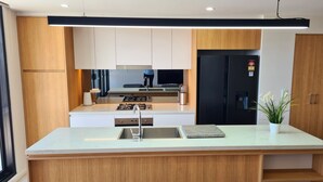 Een moderne keuken met een centraal eiland, roestvrijstalen apparatuur en houten kastjes.