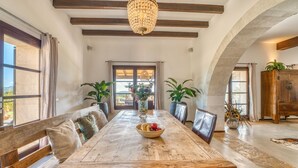 A dining area with a wooden table, benches, potted plants, and a chandelier. - Awesome home in Son Macia with private swimming pool, can be inside or outside (Son Macia)