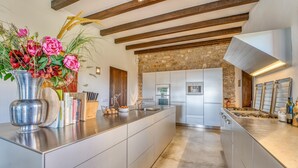 A modern kitchen with a central island, stainless steel appliances, and a stone accent wall. - Awesome home in Son Macia with private swimming pool, can be inside or outside (Son Macia)