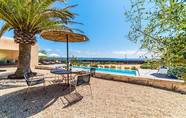 A patio with a pool, outdoor seating, and a view of the sea. - Awesome apartment in Colonia de Sant Jordi (Colonia de Sant Jordi)