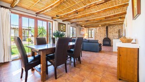 A spacious dining area with a wooden table and chairs, a sofa, and a stone fireplace. - Luxurious home in Moscari with private swimming pool, can be inside or outside (Moscari)