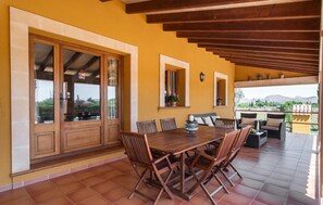 A dining area with a wooden table and chairs, large windows, and a view of the outdoors. - Gorgeous home in Pollenca with private swimming pool, can be inside or outside (Pollenca)