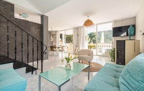A modern living room with a staircase, a dining area, and a balcony with a view. - Beautiful home in Sa Font de Sa Cala (Sa Font de Sa Cala)