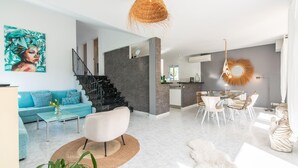 A modern living room with a sofa, coffee table, and a dining area with chairs and a table. - Beautiful home in Sa Font de Sa Cala (Sa Font de Sa Cala)