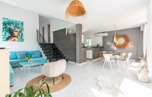 A modern living room with a sofa, coffee table, and a dining area with chairs and a table. - Beautiful home in Sa Font de Sa Cala (Sa Font de Sa Cala)