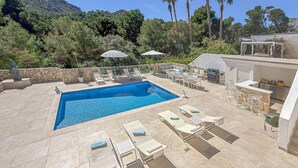 A swimming pool with lounge chairs, a barbecue area, and a stone wall. - Beautiful home in Sa Font de Sa Cala (Sa Font de Sa Cala)