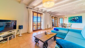 A living room with a TV, a coffee table, a sofa, and a dining area with chairs. - Gorgeous home in Calvia with sauna (Calvia)