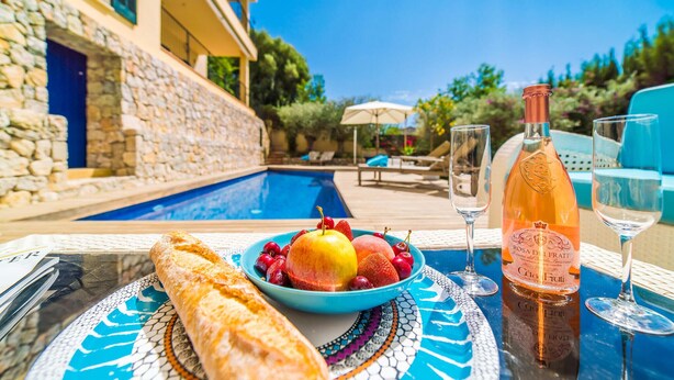 A poolside table with a bottle of rosé, two glasses, a baguette, and a bowl of fruit. - Gorgeous home in Calvia with sauna (Calvia)