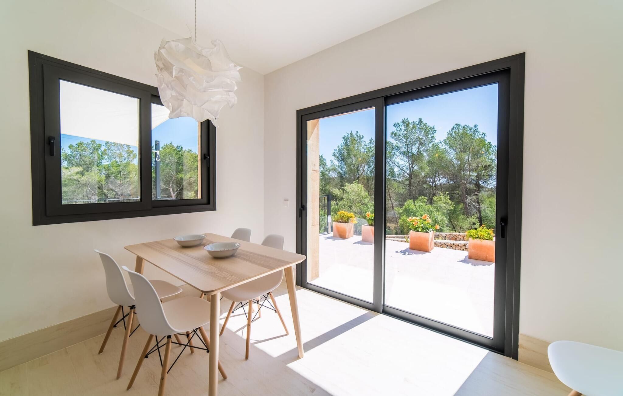 Un'area pranzo moderna con tavolo e sedie in legno, ampie finestre e vista sull'esterno.