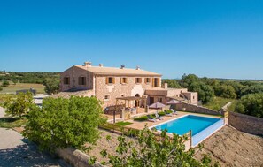 Una villa de piedra con piscina, mobiliario de exterior y vistas al campo.