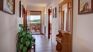 Een gang met houten deuren, ingelijste kunstwerken en een potplant.