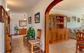 A cozy living room with a wooden cabinet, a dining table with chairs, and a sofa. - Stunning home in Cala dOr with private swimming pool, can be inside or outside (Cala dOr)