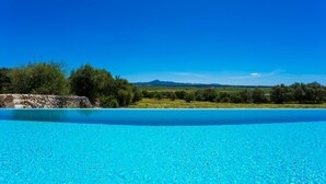 Ein klares, blaues Schwimmbecken mit einer Steinmauer und Bäumen im Hintergrund.