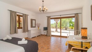 A hotel room with a bed, a desk with a TV, a chair, and a view of the outdoors. - Stunning home in Felanitx with private swimming pool, can be inside or outside (Felanitx)